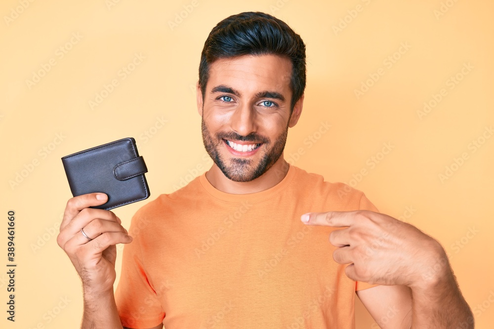 Young hispanic man holding leather wallet pointing finger to one self smiling happy and proud Young hispanic man holding leather wallet pointing finger to one self smiling happy and proud