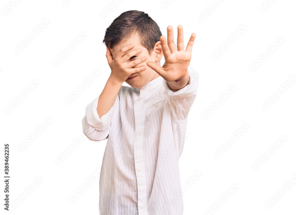 Cute blond kid wearing elegant shirt covering eyes with hands and doing stop gesture with sad and fear expression. embarrassed and negative concept. Cute blond kid wearing elegant shirt covering eyes with hands and doing stop gesture with sad and fear expression. embarrassed and negative concept.