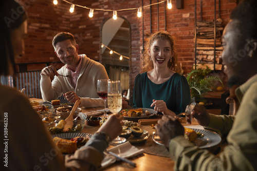Canvas Print Group of cheerful adult people sitting at dinner table while enjoying party with