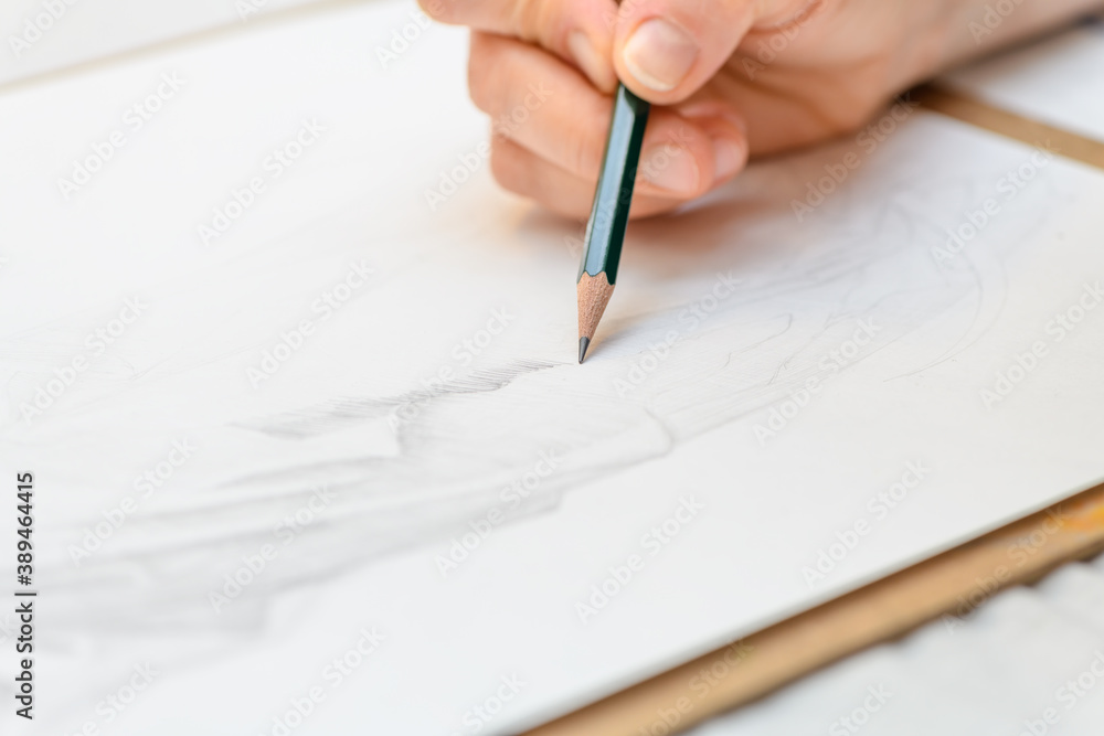 Human hand is drawing and hatching on white paper by lead pencil. Close up view. Human hand is drawing and hatching on white paper by lead pencil. Close up view.