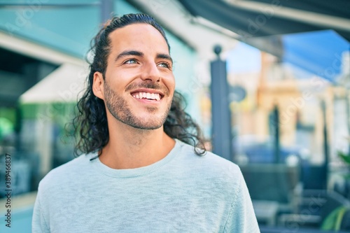 Young hispanic man smiling happy looking to the side at city.