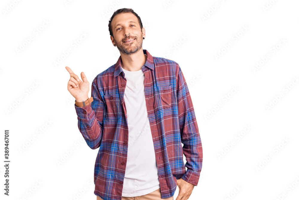 Young handsome man wearing casual clothes with a big smile on face, pointing with hand finger to the side looking at the camera. Young handsome man wearing casual clothes with a big smile on face, pointing with hand finger to the side looking at the camera.