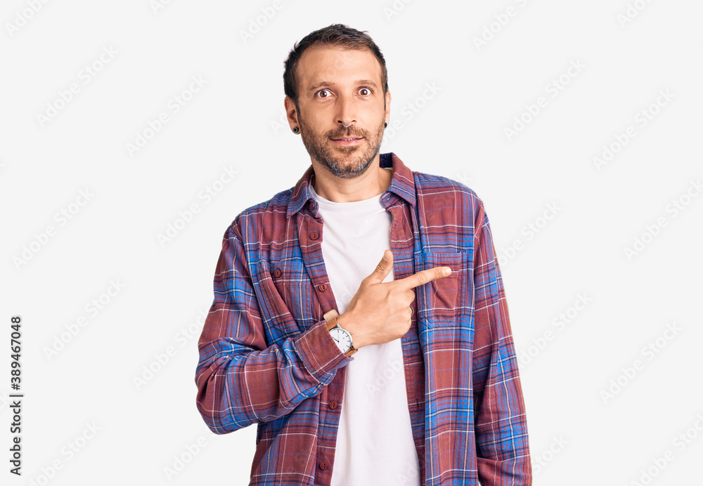 Young handsome man wearing casual clothes pointing aside worried and nervous with forefinger, concerned and surprised expression Young handsome man wearing casual clothes pointing aside worried and nervous with forefinger, concerned and surprised expression