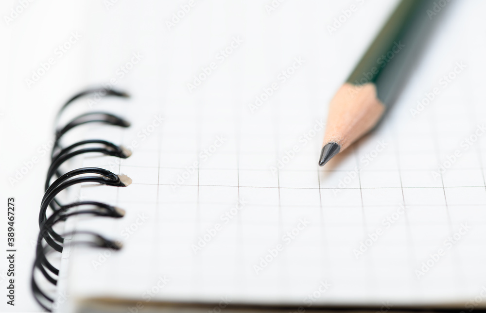 Lead pencil is on blank page of the notebook. Selective focus on the tip of a pencil. Close up view Lead pencil is on blank page of the notebook. Selective focus on the tip of a pencil. Close up view