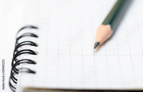 Lead pencil is on blank page of the notebook. Selective focus on the tip of a pencil. Close up view