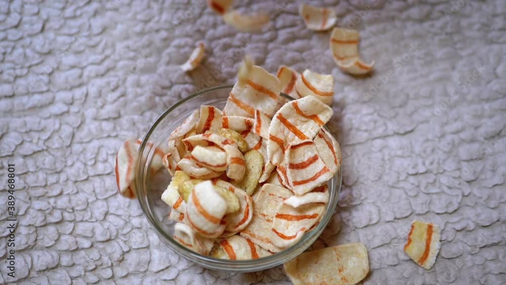 Appetizing Yellow Fried Potato Chips with Bacon Falling into Glass Bowl on Table Appetizing Yellow Fried Potato Chips with Bacon Falling into Glass Bowl on Table