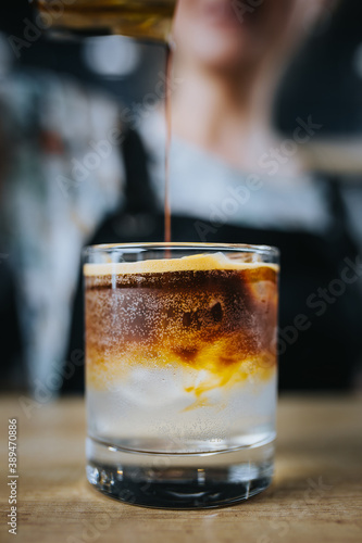 Fotografie Adding coffee to a glass with ice and lime tonic - iced coffee