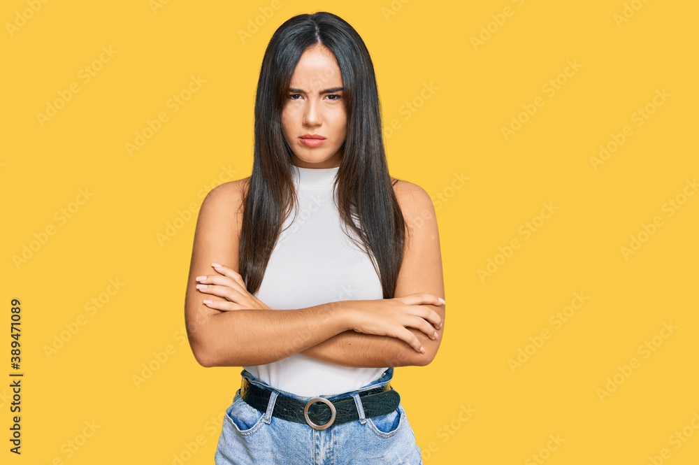 Young beautiful hispanic girl wearing casual clothes skeptic and nervous, disapproving expression on face with crossed arms. negative person. Young beautiful hispanic girl wearing casual clothes skeptic and nervous, disapproving expression on face with crossed arms. negative person.