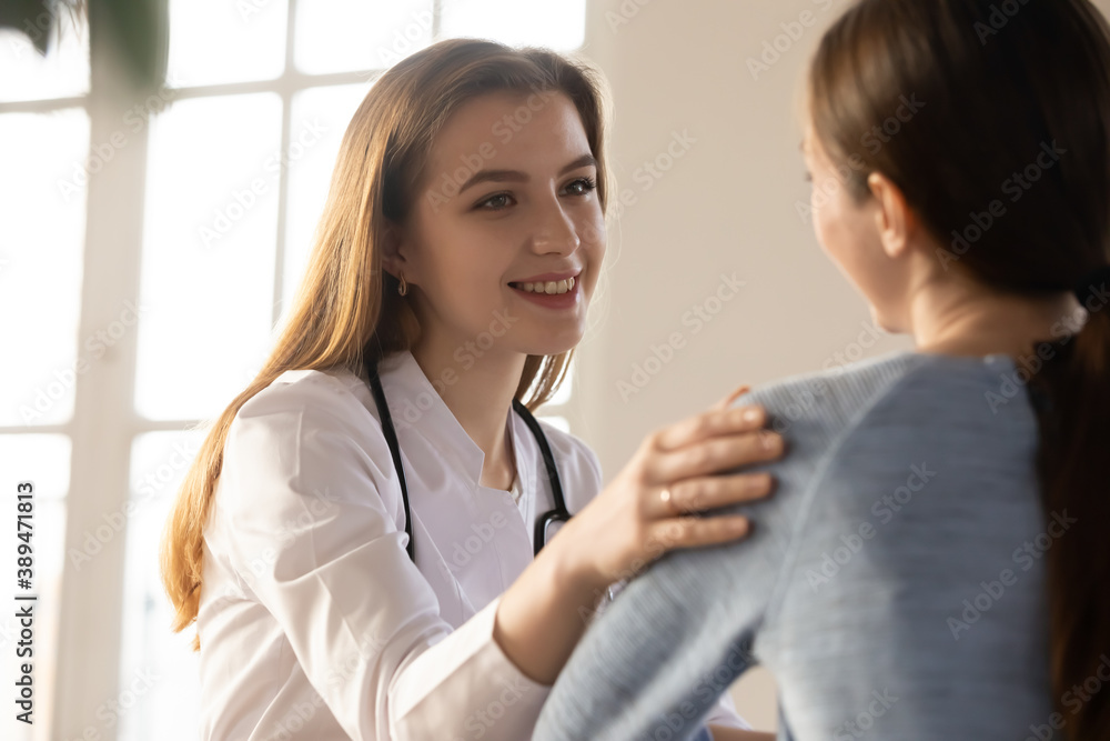 Smiling confident young woman doctor sharing good news of successful treatment or lab tests results with happy female patient, glad family therapist telling client of clinic about discarding diagnosis Smiling confident young woman doctor sharing good news of successful treatment or lab tests results with happy female patient, glad family therapist telling client of clinic about discarding diagnosis