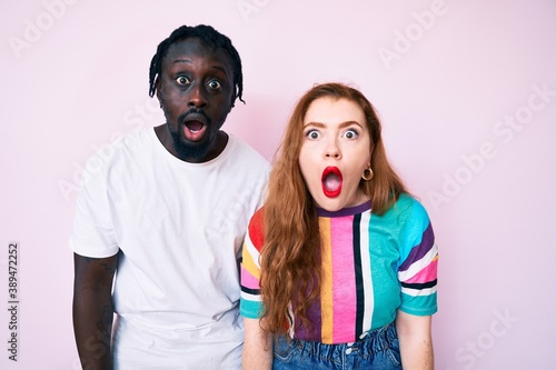 Interracial couple wearing casual clothes afraid and shocked with surprise and amazed expression, fear and excited face.