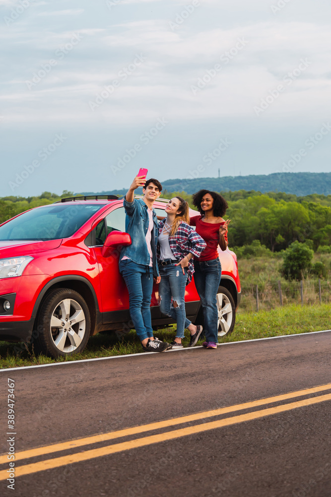 Happy young people taking selfies in route. Friends enjoying a trip.