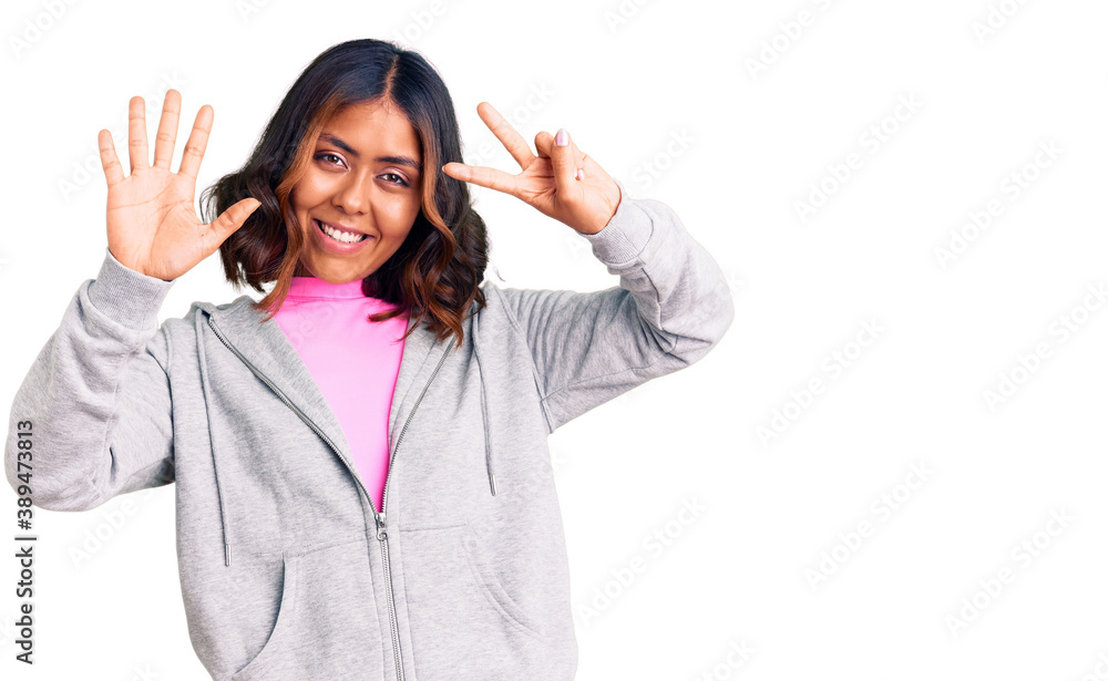 Young beautiful mixed race woman wearing casual sporty clothes showing and pointing up with fingers number seven while smiling confident and happy. Young beautiful mixed race woman wearing casual sporty clothes showing and pointing up with fingers number seven while smiling confident and happy.
