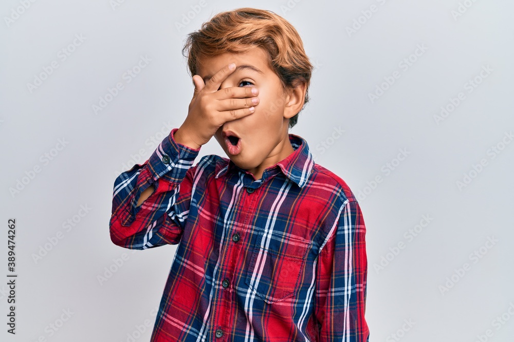 Adorable latin kid wearing casual clothes peeking in shock covering face and eyes with hand, looking through fingers afraid Adorable latin kid wearing casual clothes peeking in shock covering face and eyes with hand, looking through fingers afraid