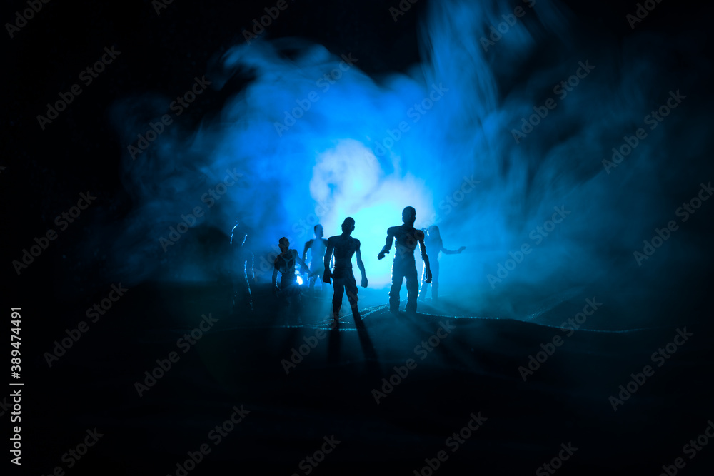 Fototapeta premium Scary view of zombies at cemetery dead tree, moon, church and spooky cloudy sky with fog, Horror Halloween concept with glowing pumpkin. Selective focus