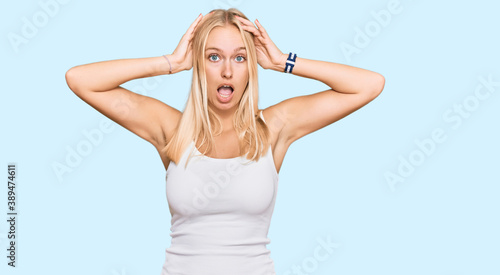 Young blonde girl wearing casual style with sleeveless shirt crazy and scared with hands on head, afraid and surprised of shock with open mouth