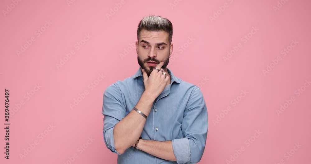 young handsome casual man with his arms crossed is thinking about something, rubbing his beard then figuring out a solution on pink background young handsome casual man with his arms crossed is thinking about something, rubbing his beard then figuring out a solution on pink background