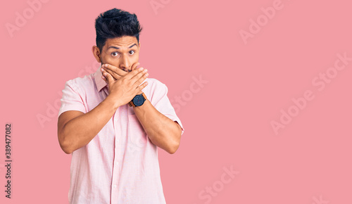 Handsome latin american young man wearing casual summer shirt shocked covering mouth with hands for mistake. secret concept.