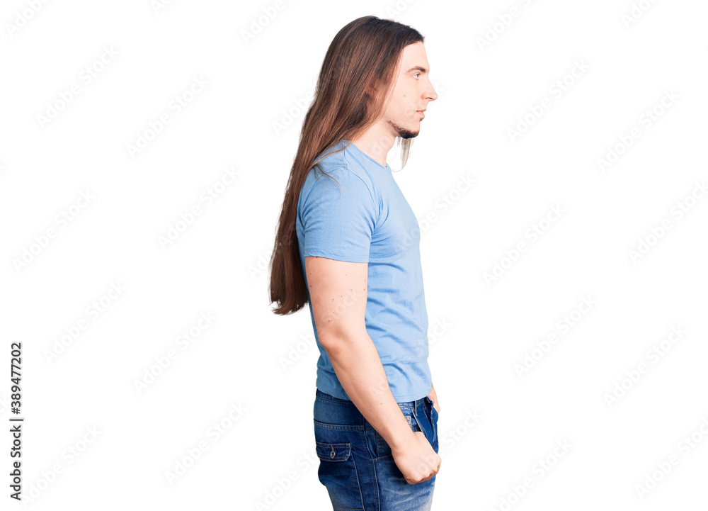 Young adult man with long hair wearing casual clothes looking to side, relax profile pose with natural face with confident smile. Young adult man with long hair wearing casual clothes looking to side, relax profile pose with natural face with confident smile.