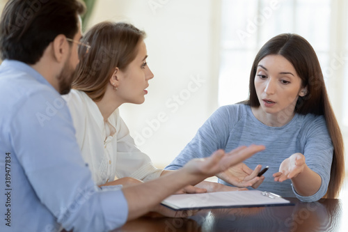 We shall complain to your superiors. Angry worried annoyed young family couple customers clients dissatisfied with bad unfair contract conditions, arguing with agent consultant lawyer prove their case