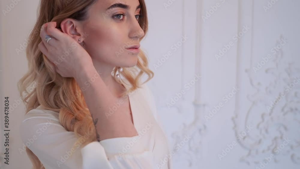 Beautiful elegant bride in a simple white wedding dress with sleeves portrait with modern pearl earrings Beautiful elegant bride in a simple white wedding dress with sleeves portrait with modern pearl earrings