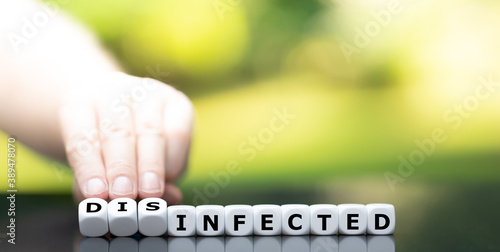 Hand turns dice and changes the word "infected" to "disinfected".
