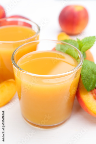 Natural peach juice and fresh fruits on white wooden table, closeup