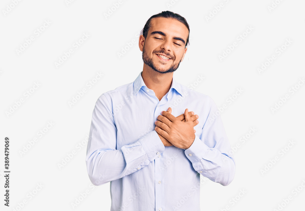 Young handsome man wearing business clothes smiling with hands on chest with closed eyes and grateful gesture on face. health concept. Young handsome man wearing business clothes smiling with hands on chest with closed eyes and grateful gesture on face. health concept.