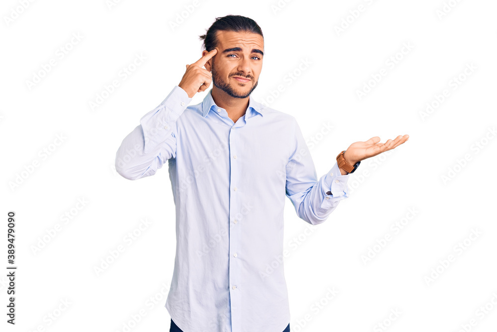 Young handsome man wearing business clothes confused and annoyed with open palm showing copy space and pointing finger to forehead. think about it. Young handsome man wearing business clothes confused and annoyed with open palm showing copy space and pointing finger to forehead. think about it.