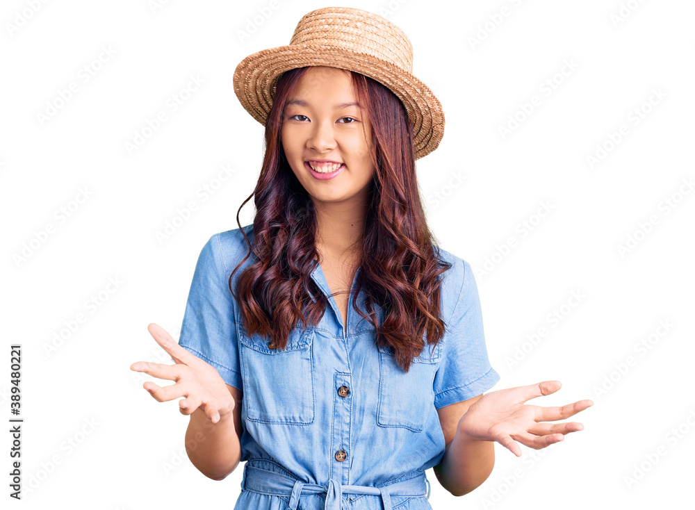 Young beautiful chinese girl wearing summer hat smiling cheerful with open arms as friendly welcome, positive and confident greetings Young beautiful chinese girl wearing summer hat smiling cheerful with open arms as friendly welcome, positive and confident greetings