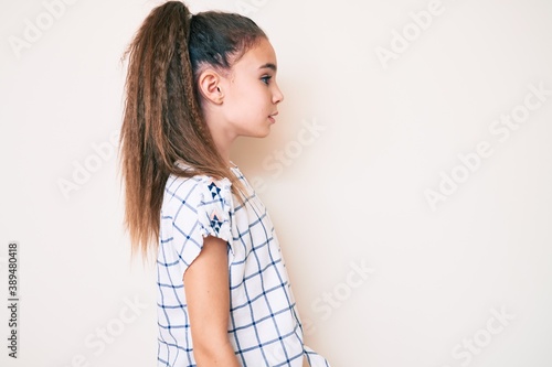 Cute hispanic child girl wearing casual clothes looking to side, relax profile pose with natural face with confident smile.
