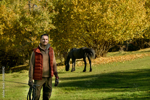 A black horse and a a man on a sunny autumn day. © xpabli