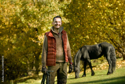 A black horse and a a man on a sunny autumn day.