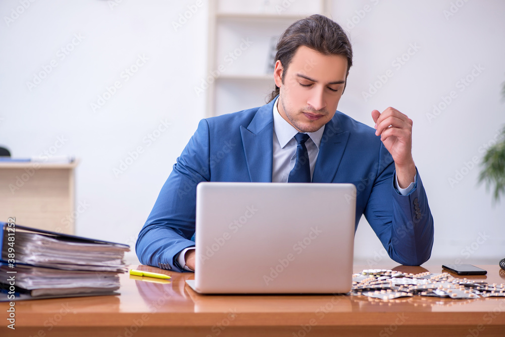 Young male sick employee suffering at workplace Young male sick employee suffering at workplace