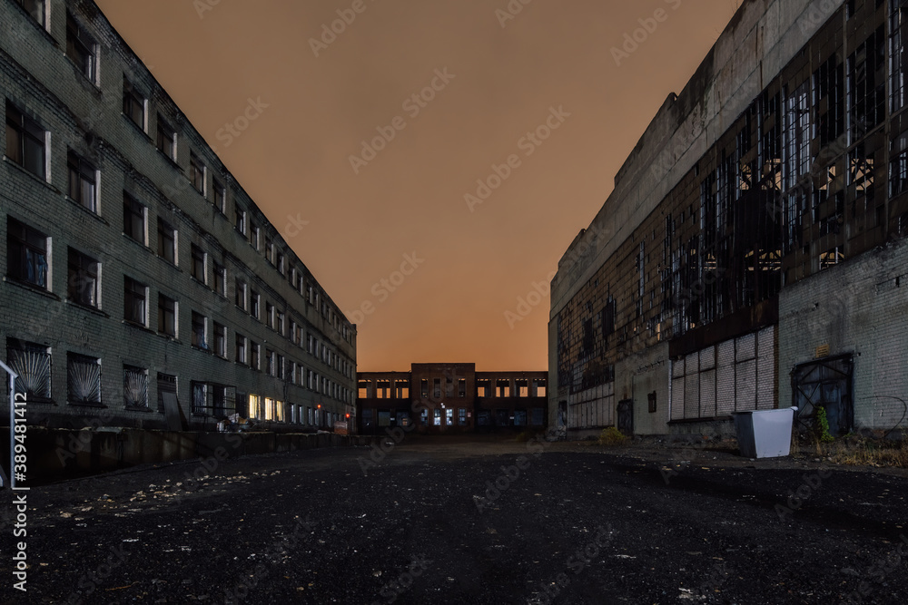 Territory of abandoned industrial area waiting for demolition at night. Broken and burnt buildings