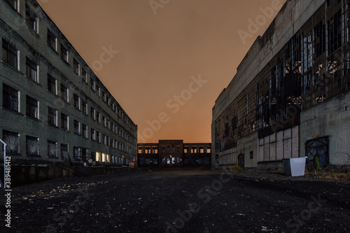 Territory of abandoned industrial area waiting for demolition at night. Broken and burnt buildings