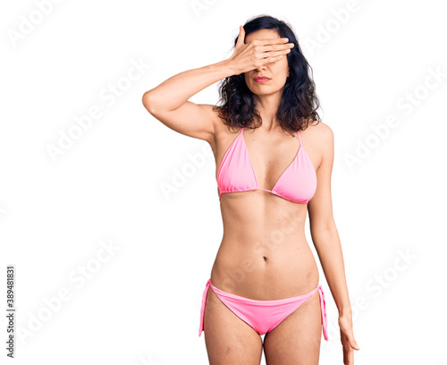 Young beautiful hispanic woman wearing bikini covering eyes with hand, looking serious and sad. sightless, hiding and rejection concept © Krakenimages.com