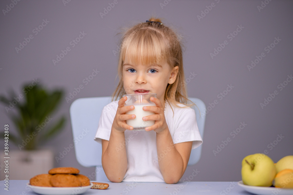 Cute little girl eating cookies and drinking milk at home or in kindergarten Cute little girl eating cookies and drinking milk at home or in kindergarten
