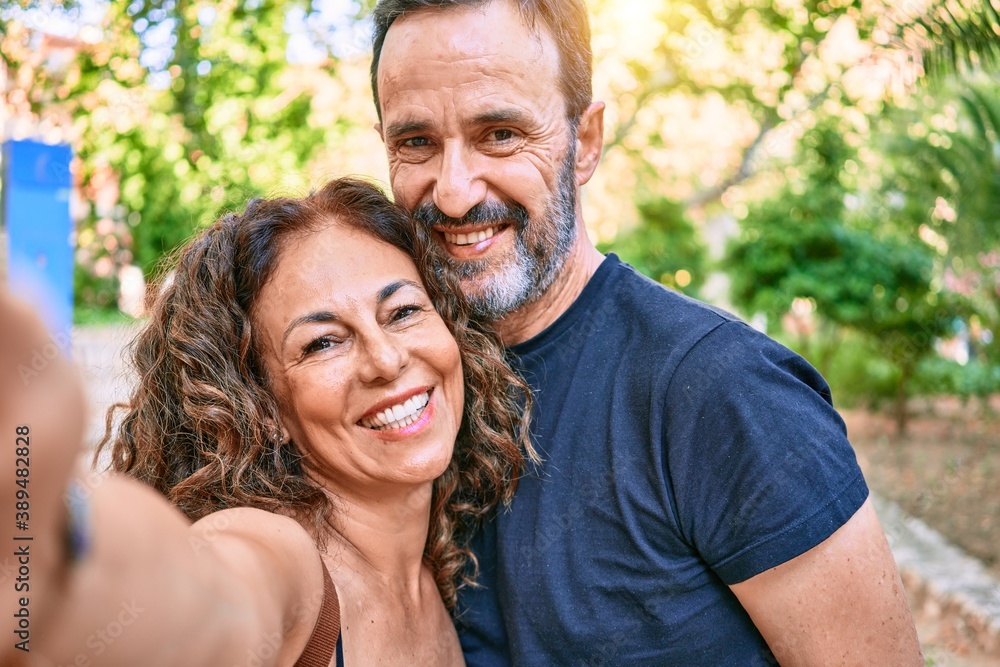 Middle age couple wearing casual clothes smiling happy making selfie by the camera at the forest Middle age couple wearing casual clothes smiling happy making selfie by the camera at the forest