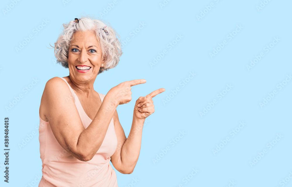 Senior grey-haired woman wearing casual clothes smiling and looking at the camera pointing with two hands and fingers to the side. Senior grey-haired woman wearing casual clothes smiling and looking at the camera pointing with two hands and fingers to the side.