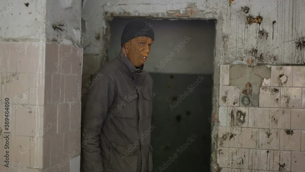 A tall man in dirty clothes and a zombie monster mask wanders through an abandoned building. Looping. A tall man in dirty clothes and a zombie monster mask wanders through an abandoned building. Looping.