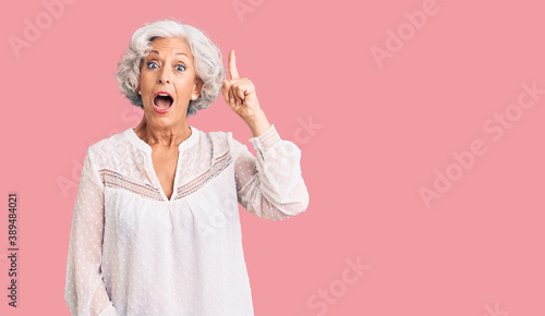 Senior grey-haired woman wearing casual clothes pointing finger up with successful idea. exited and happy. number one.