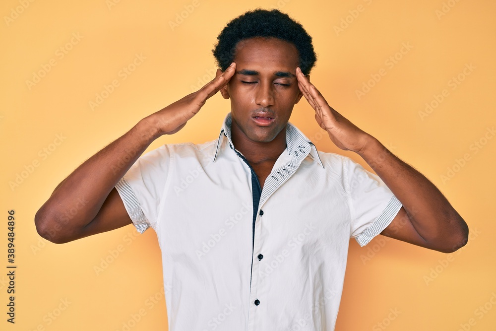 African handsome man wearing casual shirt suffering from headache desperate and stressed because pain and migraine. hands on head. African handsome man wearing casual shirt suffering from headache desperate and stressed because pain and migraine. hands on head.