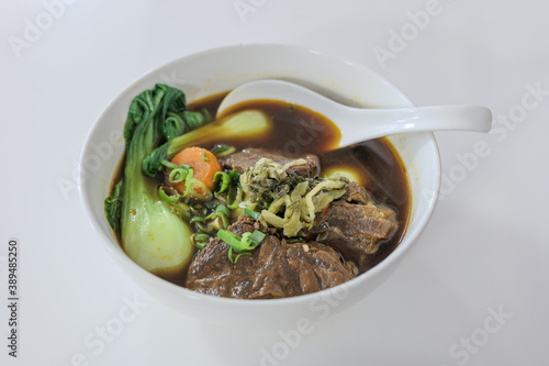 Selected focus view at Taiwanese stew Beef Noodle Soup without noodle in white bowl on white table. © Peeradontax