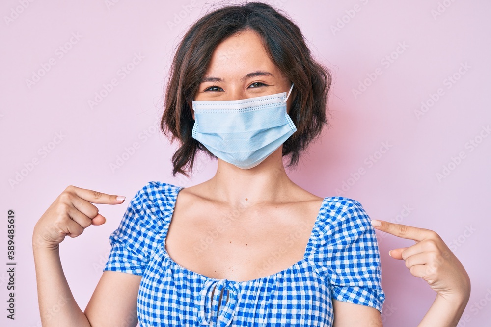 Young beautiful woman wearing medical mask looking confident with smile on face, pointing oneself with fingers proud and happy. Young beautiful woman wearing medical mask looking confident with smile on face, pointing oneself with fingers proud and happy.