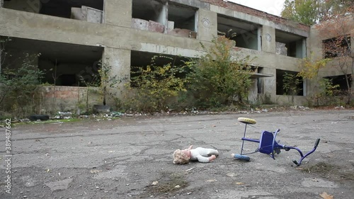 Childish tricycle and doll lie in the courtyard of an abandoned building. An abandoned area of the city. photo