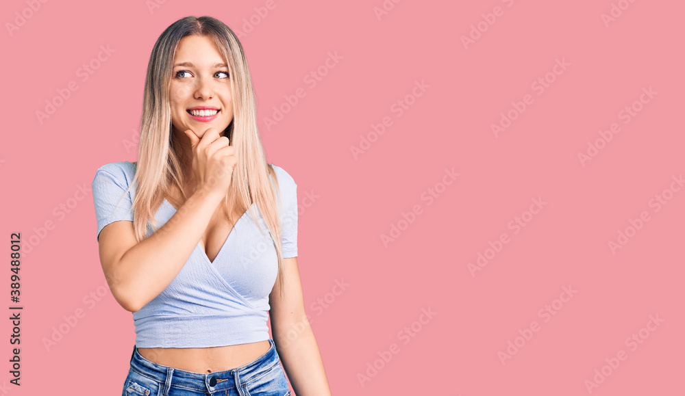 Young beautiful blonde woman wearing casual clothes with hand on chin thinking about question, pensive expression. smiling with thoughtful face. doubt concept. Young beautiful blonde woman wearing casual clothes with hand on chin thinking about question, pensive expression. smiling with thoughtful face. doubt concept.