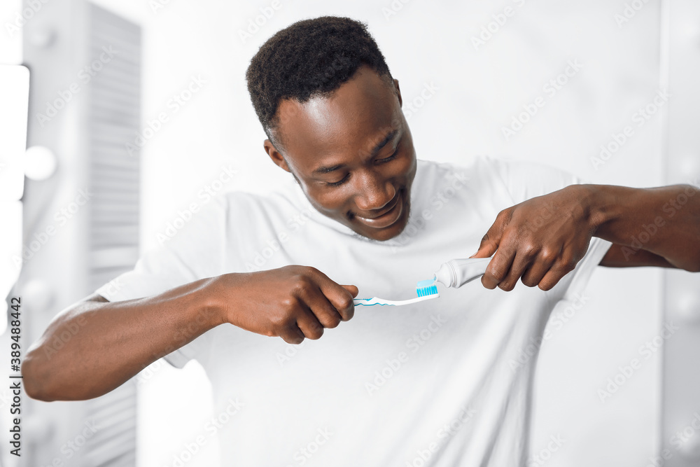 Black Guy Applying Toothpaste On Toothbrush Cleaning Teeth In Bathroom Black Guy Applying Toothpaste On Toothbrush Cleaning Teeth In Bathroom