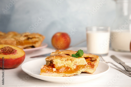 Piece of delicious fresh peach pie served on white wooden table, closeup