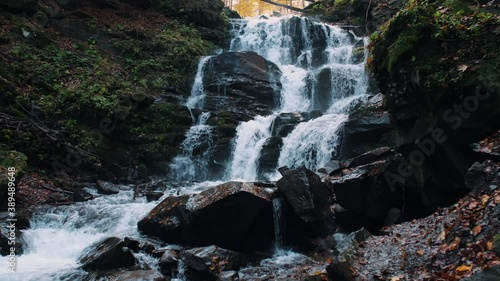 Colorful autumn landscape with yellow trees and waterfall. Beautiful nature at colorful autumn forest in fall season. Carpathian Mountains, Ukraine.