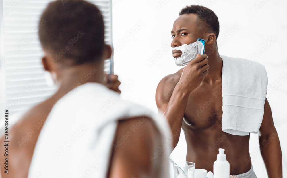 Shirtless Black Guy Shaving Face In Morning Standing In Bathroom